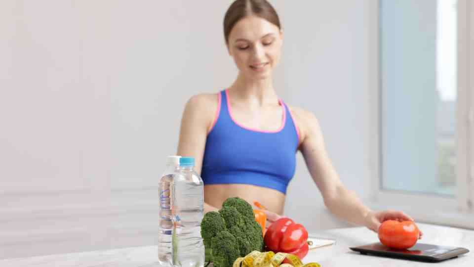 Woman in gym gear eating healthy and keeping hydrated for weight loss