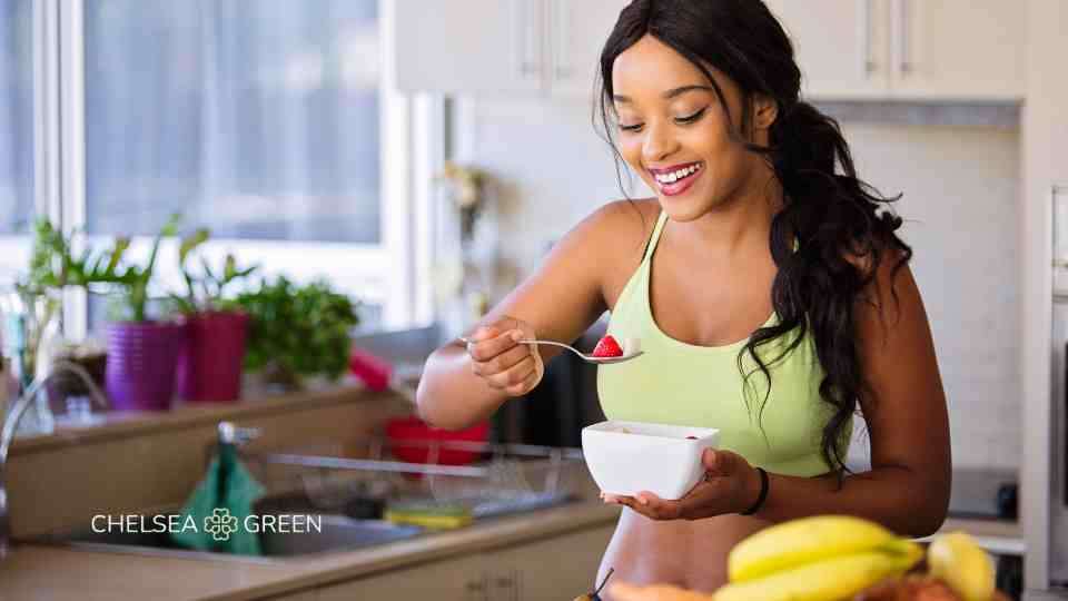 Woman eating a healthy bowl of food in her kitchen