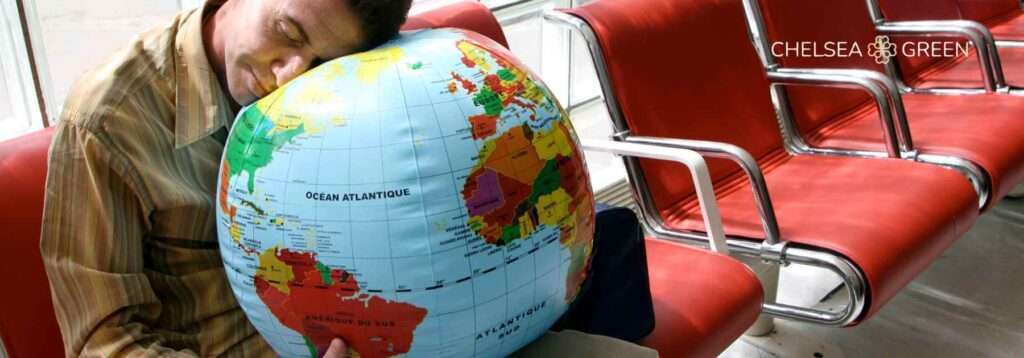 Man asleep on a blow up globe struggling with jet lag