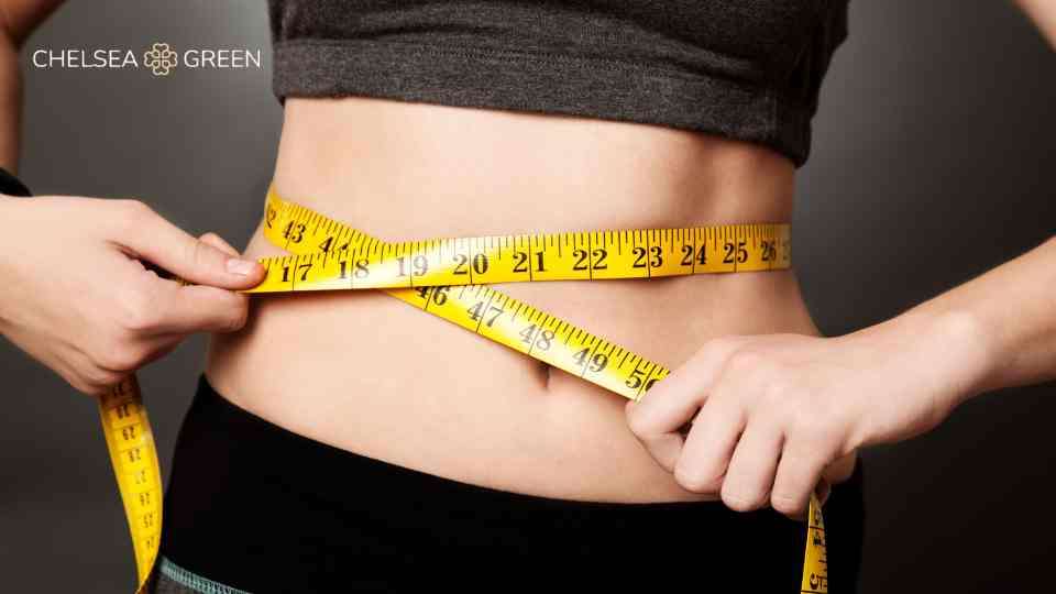 Woman who has lost weight holding tape on waist to illustrate this